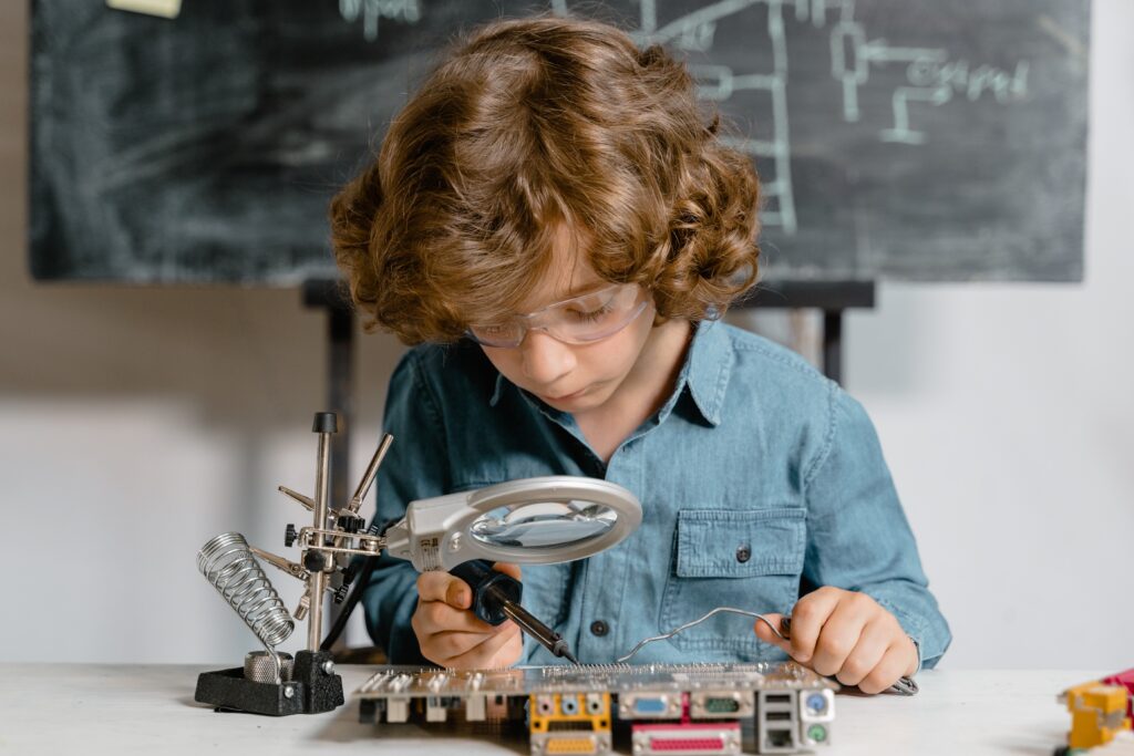 AA kid tinkers with a magnifying glass. This article covers stem fair project ideas.