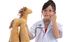 Little girl playing doctor listening to toy horse's heart with a stethescope